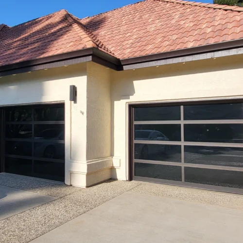 beige yellowish house with a light brown roofing and a glass garage door