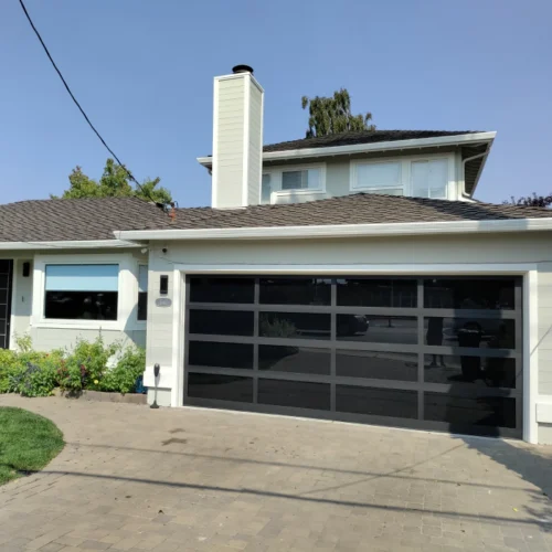 light grey house with a dark brown roofing and a black garage door
