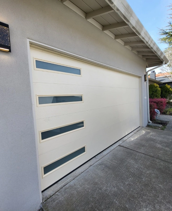 light grey house with a light beige garage door and a parking outside